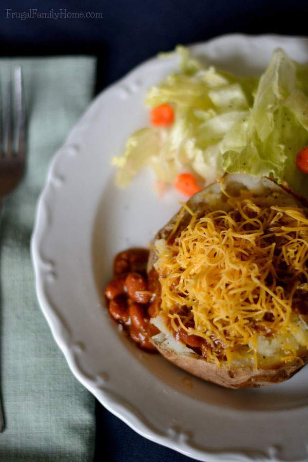 Easy to make dinner of chili baked potato bar with salad on a plate.