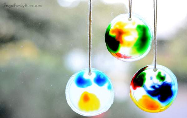 Looking for an easy to do summer fun project for the kids. These sun catchers for kids are a fun project that can be done inside or outside. If you have food coloring, glue and a container lid you have everything needed to make them. 