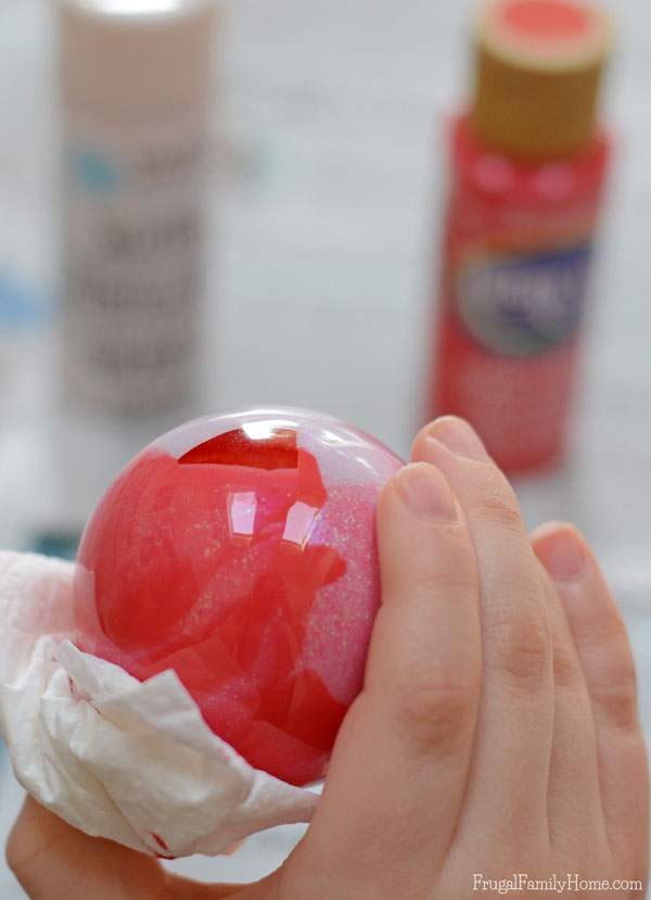 My kids had a great time making this Christmas ornaments, even though I was the one to drop and break one while it was full of paint. We used a glitter paint and watermelon red to make our swirled paint ornaments.