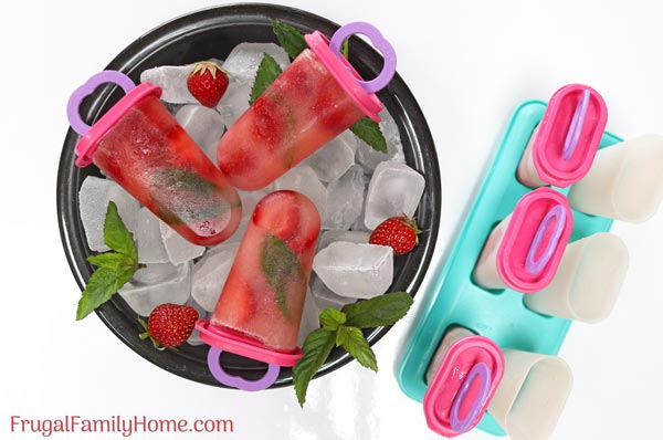 Bowl with strawberry mint popsicles next to the popsicles mold.