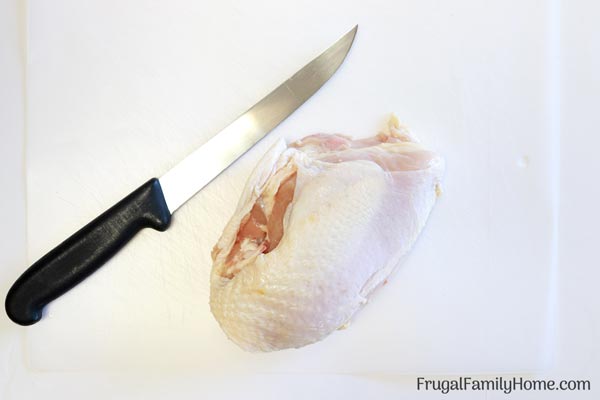 Knife and chicken on board for how to debone chicken breast