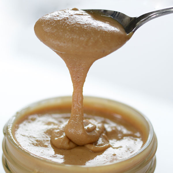 Creamy homemade peanut butter dripping from spoon