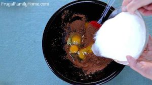 Adding sugar to eggs and cocoa powder.