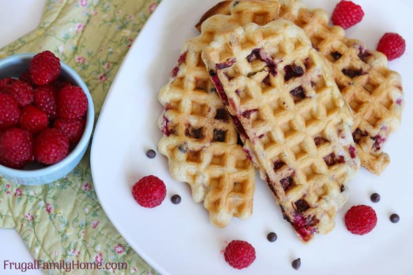 Cooked homemade waffles ready to eat with a side of raspberries.