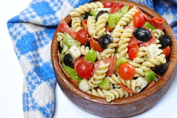 Pepperoni pasta salad in a wooden bowl ready to serve.