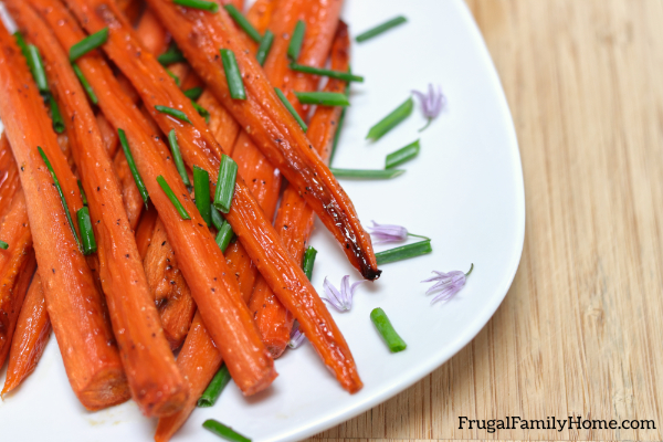 roasted carrots on a plate with chive flowers.