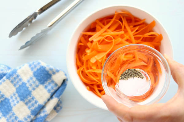 adding salt and pepper to the carrots