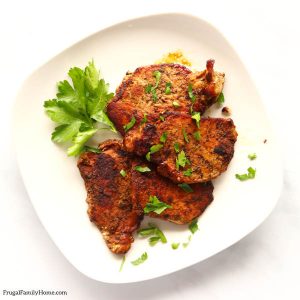 All the pork chops on a plate sprinkled with parsley.