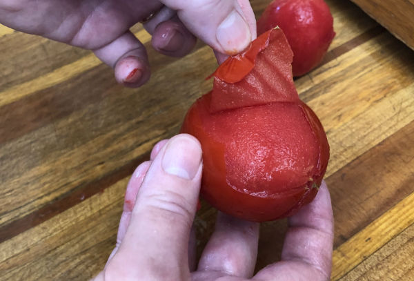 Peeling the skin off the tomato before canning