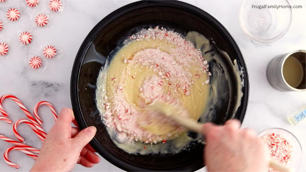 Stirring the crushed peppermint candies into the white chocolate fudge.