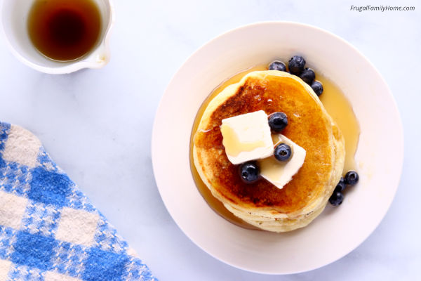 Homemade pancake syrup over pancakes with blueberries.