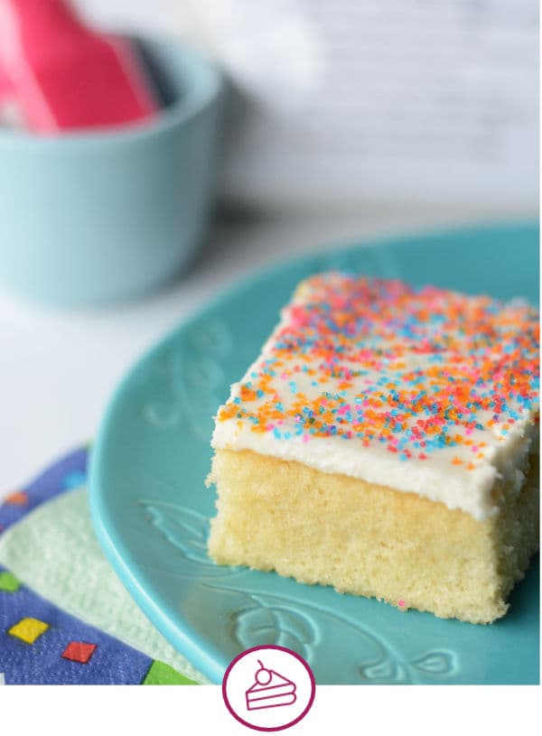 a slice of vanilla cake with white frosting and sprinkles