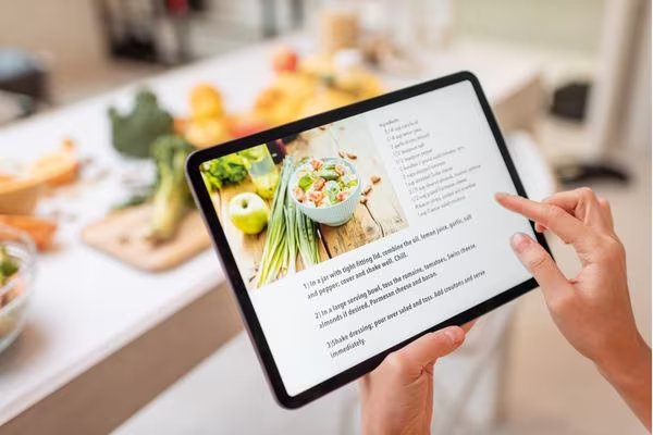 Looking at a recipe on an ipad as person is cooking.