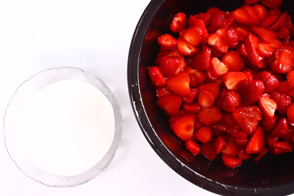 Sliced strawberries and sugar for strawberries for shortcake for the freezer.